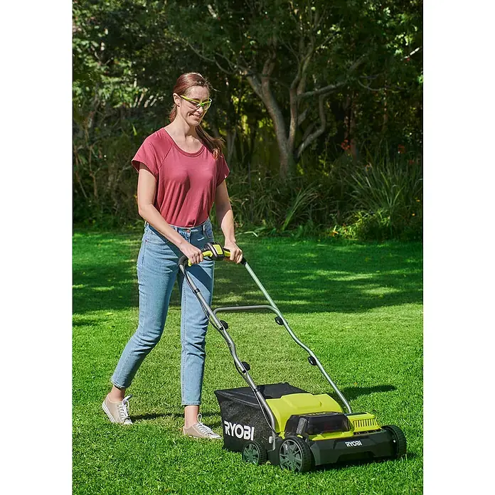 Ryobi ONE+ Akku-Vertikutierer RY18SFX35A-240 - Anzahl Akkus: 2 Akkus, 18 V, Arbeitsbreite: 35 cm - Frau benutzt einen Ryobi Rasenlüfter im Garten. Das Gerät ist gelb und schwarz und hat einen Fangkorb.