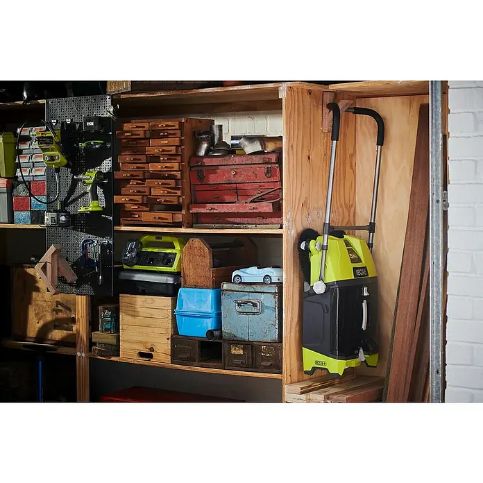 Ryobi ONE+ Akku-Handkehrmaschine R18SW3-0 - 18 V, Ohne Akku, Behältervolumen: 17 l - Ein Regal mit Werkzeugen und Geräten, darunter ein Ryobi ONE+ Kehrgerät, Holzboxen und Werkzeugkästen, typisch für eine Garage.