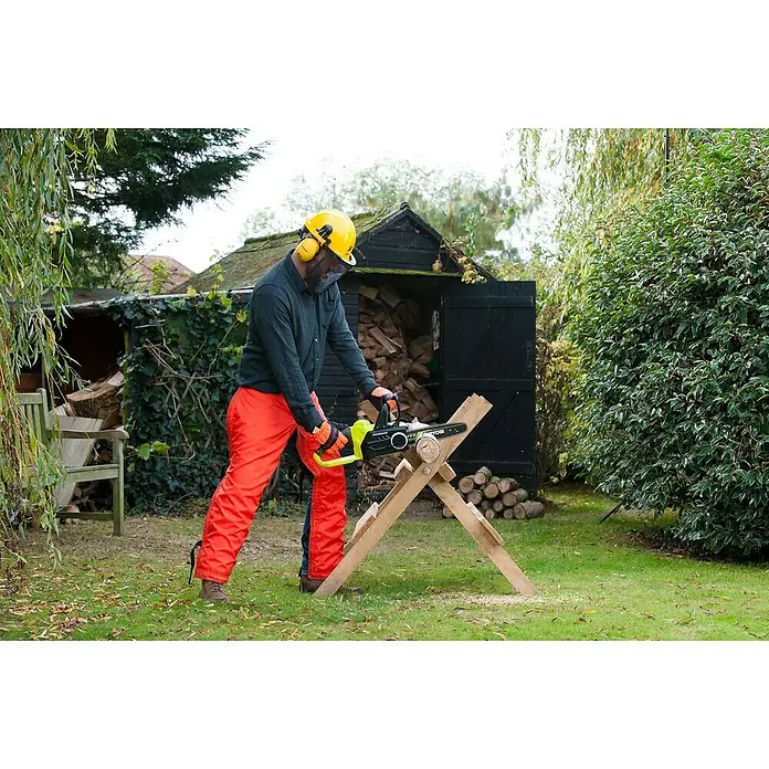 Ryobi ONE+ Akku-Kettensäge - 18 V, Li-Ionen, Ohne Akku, Schwertlänge: 30 cm - Eine Person in Schutzkleidung benutzt eine RYOBI Kettensäge, um Holz vor einem Holzschuppen zu schneiden.