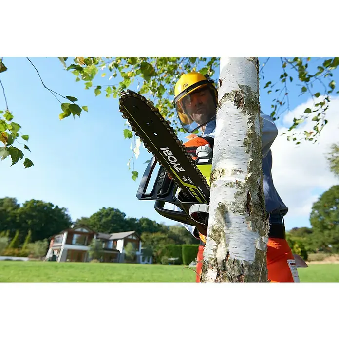 Ryobi ONE+ Maschinenpaket - Akku-Kettensäge ,18V, 4 Ah Akku & 2A Ladegerät - Mann mit gelbem Helm, der eine RYOBI-Kettensäge hält, um einen Baumstamm zu schneiden. Im Hintergrund ein Haus.