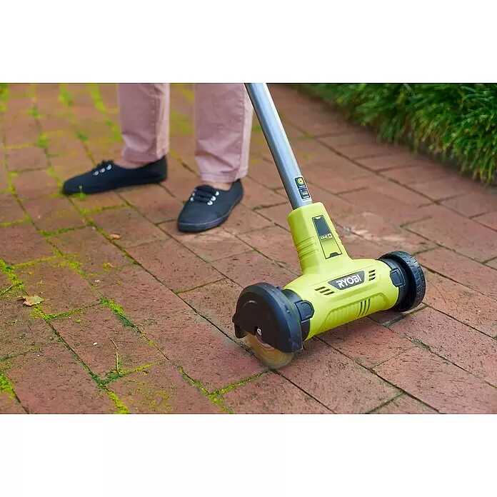 Ryobi ONE+ Limpiador de juntas de batería RY18PCA-0 - 18 V, Iones de litio, Sin batería - Una persona limpia musgo de un camino de ladrillos rojos con un limpiador de patio Ryobi ONE+ verde lima con un cepillo giratorio.