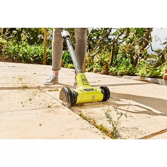 Ryobi ONE+ Limpiador de juntas de batería RY18PCA-0 - 18 V, Iones de litio, Sin batería - Una persona usa un cepillo para malas hierbas Ryobi amarillo y negro para limpiar las baldosas del patio.