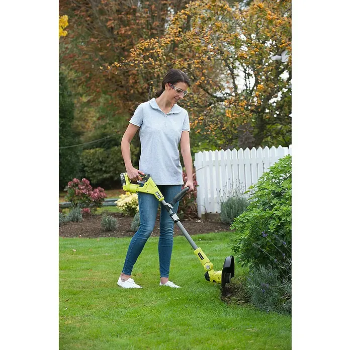 Ryobi ONE+ Hybrid-Rasentrimmer RLT1831H25F - 18 V, 2,5 Ah, Li-Ionen, 1 Akku - Frau verwendet einen gelben RYOBI Kantenschneider, um das Gras an den Rändern eines Gartens zu trimmen.