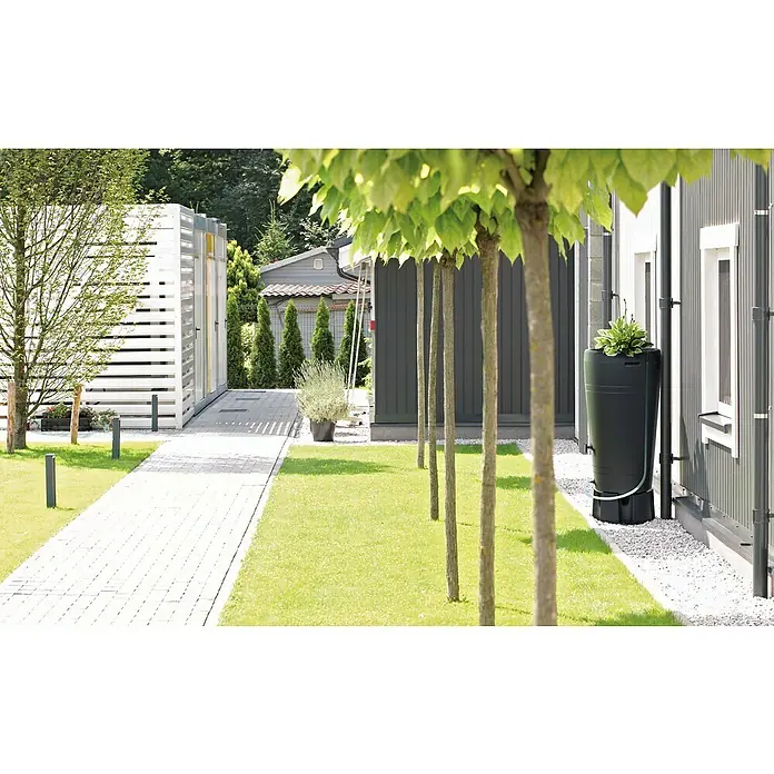 Regenspeicher Tube - 230 l, Anthrazit - Nahaufnahme eines schlanken, schwarzen Regenspeichers neben einem modernen Haus, umgeben von üppigem Grün und Bäumen.