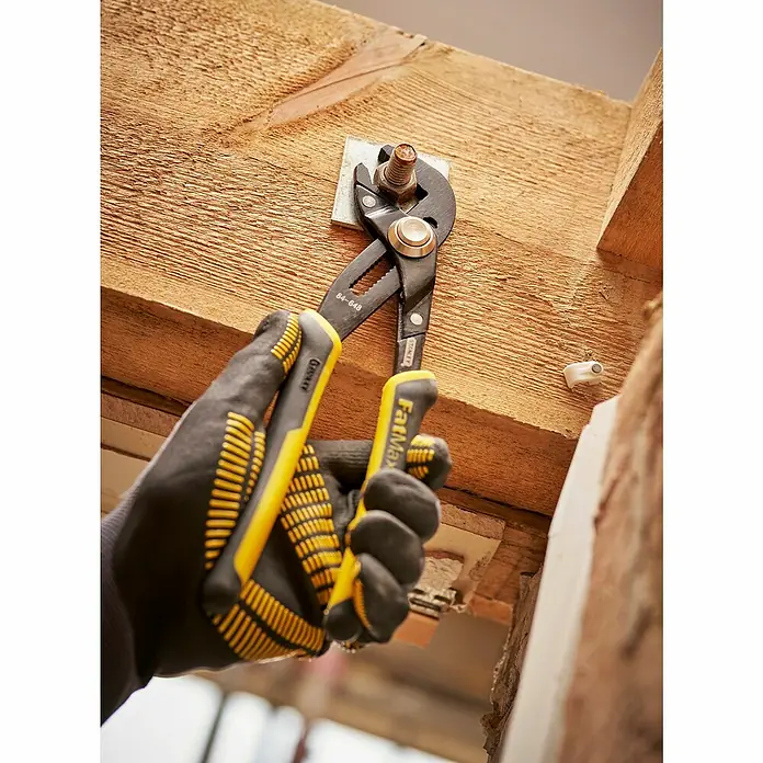 Stanley FatMax Wasserpumpenzange 0-84-648 - Länge: 254 mm - Eine Hand mit Schutzhandschuh hält eine FatMax-Rohrzange, die eine Mutter an einem Holzbalken festzieht.
