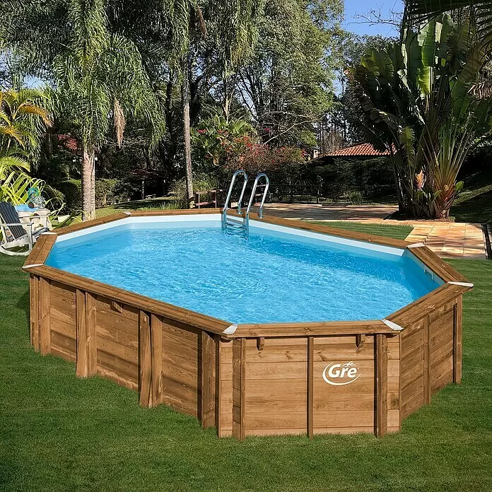 Gre Holz-Pool Safran 2 - L x B x H: 620 x 395 x 136 cm, Hellbraun, 22.000 l - Ein ovales Aufstellbecken mit Holzrahmen und blauem Wasser, in einem sonnigen, grünen Garten.