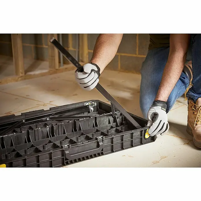 Stanley Werkbank ESSENTAIL™ STST83492-1 - L x B: 85 x 61 cm, Arbeitshöhe: 80 cm, Belastbarkeit: 320 kg, Schwarz/Gelb - Eine Person öffnet einen schwarzen Werkzeugkasten. Der Kasten hat viele Fächer und ist ideal für die Aufbewahrung von Werkzeugen.