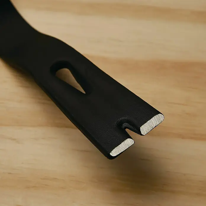 Stanley Präzisionseisen SUPER WONDER BAR 1-55-525 - 380 x 400 mm - Nahaufnahme eines schwarzen Brecheisens mit Nagelklaue auf einem hellen Holztisch. Das Werkzeug ist scharf und bereit für den Einsatz.