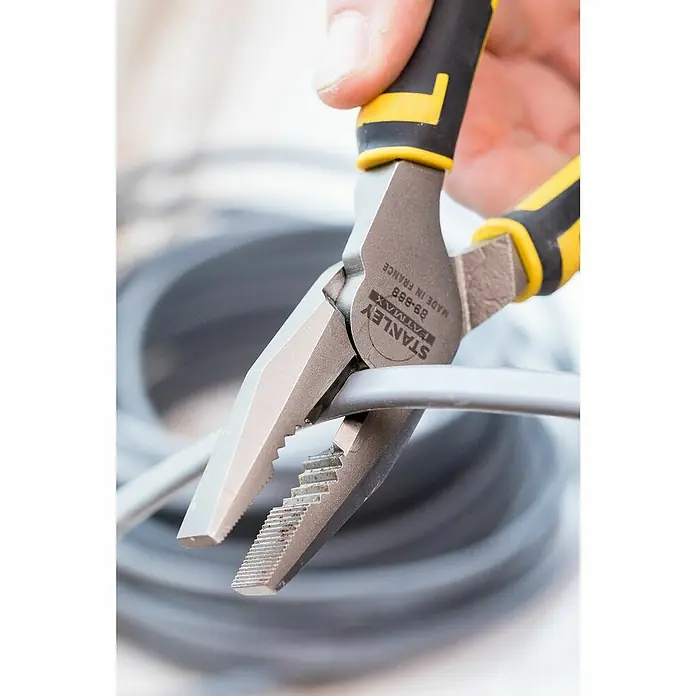 Stanley FatMax Kombizange FATMAX 0-89-868 - Länge: 20 cm - Nahaufnahme einer Stanley FatMax Kombizange, die ein graues Kabel hält. Die Zange hat gelb-schwarze Griffe und ist ideal zum Greifen und Schneiden.