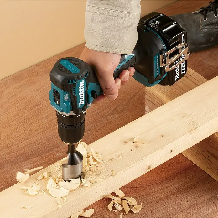 Makita LXT 18V Akku-Bohrschrauber DDF487Z - 18 V, Ohne Akku - Die Makita Akku-Bohrmaschine beim Bohren in ein Holzbrett, umgeben von Spänen. Leistungsstarkes Werkzeug für präzise Arbeiten.
