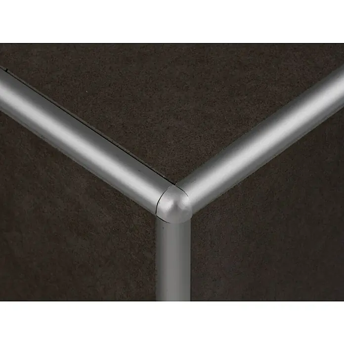 Perfil para baldosas ECO 171 A - Aluminio, Plateado, 2,5 m x 10 mm, Mate - Primer plano de una esquina con un marco metálico plateado, destacando un elemento de diseño moderno y minimalista.