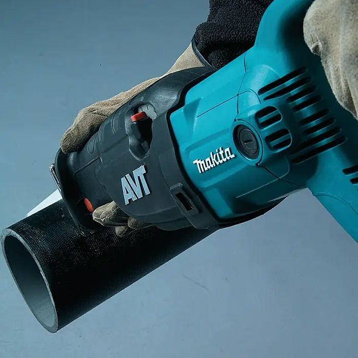 Makita Sierra de sable JR3070CT - 1.510 W, Longitud de carrera: 32 mm - Primer plano de una sierra de sable Makita cortando una tubería, sostenida por una persona con guantes.