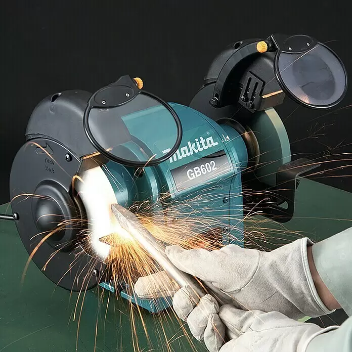 Makita Esmeriladora doble eléctrica GB602 - 250 W, 2.850 r.p.m. - Esmeriladora de banco Makita GB602 turquesa en uso, afilando una barra metálica y produciendo chispas; manos con guantes.