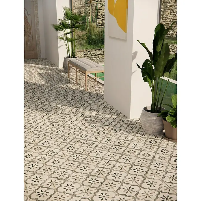 Pavimento porcelánico hidráulico Leeds - 45 x 45 cm, Gris/Crema, Mate - Un área exterior elegante con baldosas decorativas que crean un ambiente elegante. Plantas y una zona de estar complementan el diseño.