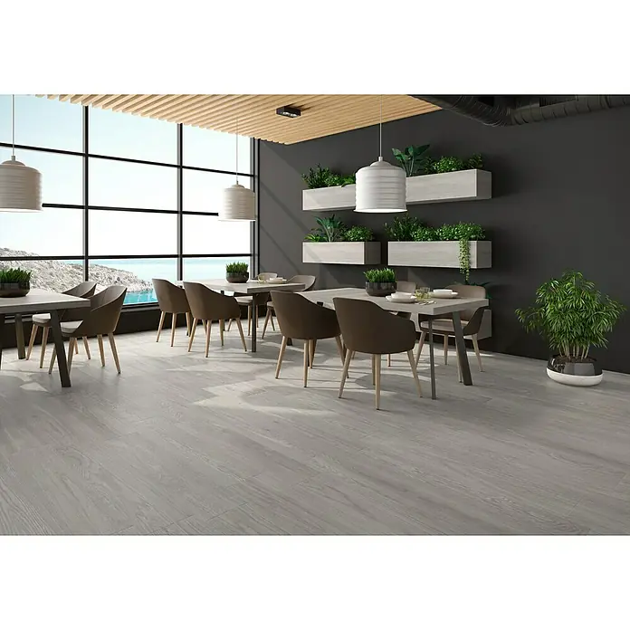 Pavimento porcelánico Noe - 120 x 23 cm, Gris, Mate - Los azulejos claros con aspecto de madera le dan un toque moderno a este restaurante. La decoración de madera gris combina con los muebles.