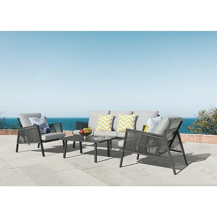 Sunfun Conjunto de muebles Keira - 4 pzs., Aluminio, Antracita - Elegante conjunto de muebles de patio con sillones grises, un sofá, una mesa y cojines decorativos con una vista serena al mar.