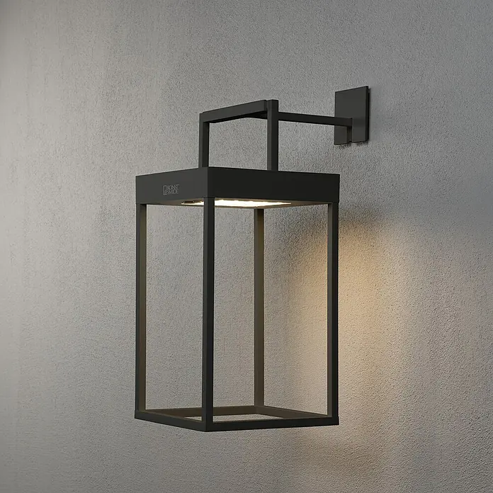 Konstsmide Außenlaterne Portofino - 15,5 x 18,5 x 30 cm, Schwarz - Moderne schwarze Außenwandleuchte mit rechteckigem Rahmen und warmem Lichtschein an einer grauen Wand.