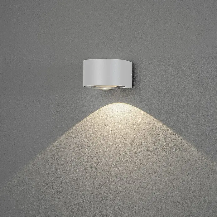 Konstsmide LED-Außenwandleuchte Gala - 6 W, Weiß, IP54 - Moderne weiße Wandleuchte, die ein warmes, einladendes Licht an einer grauen Wand ausstrahlt. Elegantes Design für Innenräume.