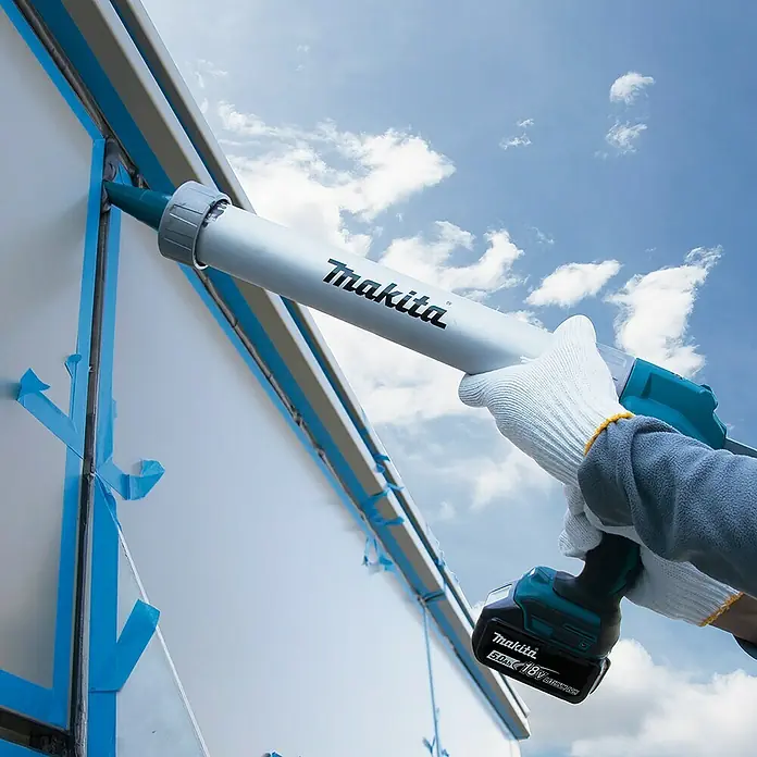 Makita LXT 18V Akku-Kartuschenpresse DCG180ZX - 18 V, Li-Ionen, Ohne Akku - Nahaufnahme einer Makita-Akku-Dichtpistole im Einsatz beim Abdichten eines Fensters. Ideal für Handwerker und Heimwerker.