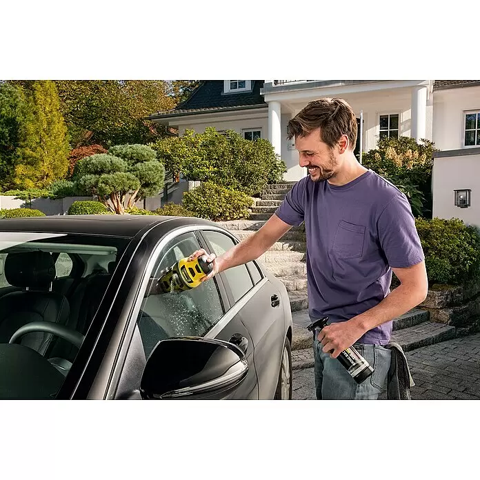 Kärcher Reinigungs-Set - 4 -tlg., Passend für: Kärcher Akku-Eiskratzer EDI 4 - Ein Mann reinigt eine Autoscheibe mit einem gelb-schwarzen Fenstersauger und hält eine Sprühflasche in der anderen Hand.