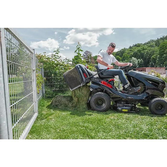 AL-KO Easy Rasentraktor T 15-93.2 HD-A - 452 cm³, Schnittbreite: 93 cm, Schnitthöhe: 80 mm - Rasenmäher mit vollem Fangkorb wird in der Nähe eines Zauns entleert.