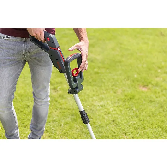 AL-KO Bosch Home & Garden Compatible Akku-Rasentrimmer GT 1825 - 18 V, 2,5 Ah, Li-Ionen, 1 Akku, Schnittbreite Faden: 25 cm - Nahaufnahme eines Mannes, der einen AL-KO Akku-Rasentrimmer in einem Garten bedient, mit Fokus auf Design und Ergonomie des Trimmers.