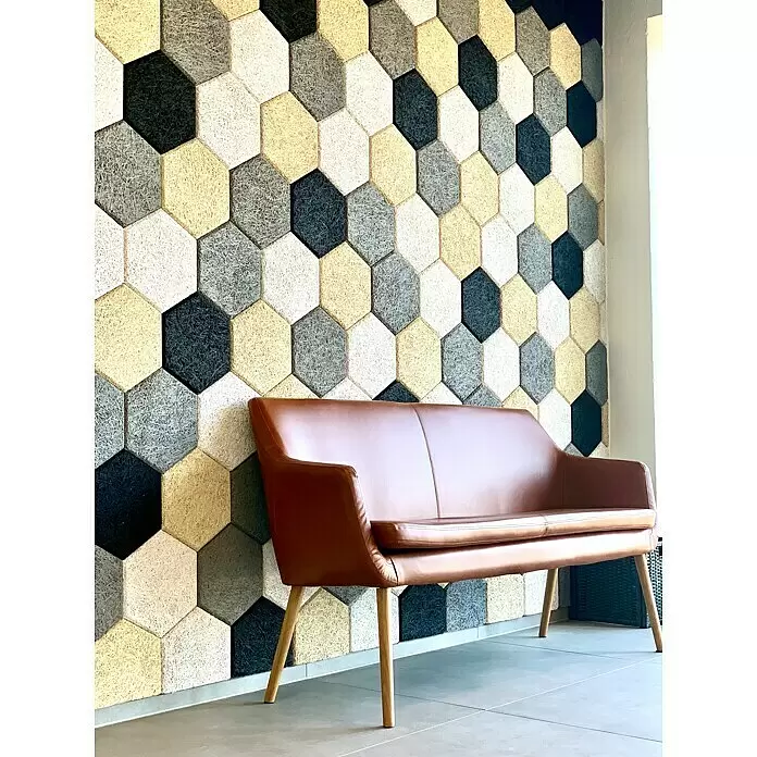 FibroTech Akustikplatte Hexagon - Beige, 250 x 289 x 25 mm, 18 Stk., 0,972 m² - Braunes Ledersofa mit Holzbeinen vor einer strukturierten sechseckigen Wand in Creme, Grau und Schwarz.