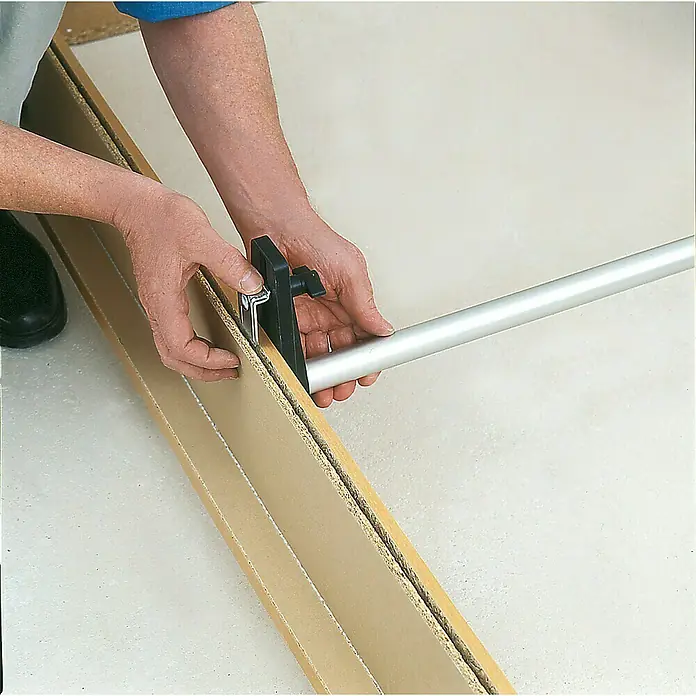 Bessey Türfuttermontagestrebe TMS - Spannweite: 560 mm - 1.010 mm - Detailaufnahme einer Person, die eine Nutfräse zum Bearbeiten eines Holzstücks verwendet. Präzise Holzbearbeitung im Fokus.