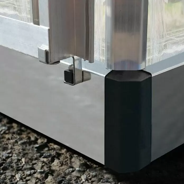 Palram – Canopia Gewächshaus Hybrid - Außenmaß inkl. Dachüberstand (B x T): 185 x 306 cm, 0,7 mm, Silber - Nahaufnahme einer silbergrauen Aluminiumrahmenecke mit schwarzem achteckigem Protektor und Metallklammern auf dunklem Untergrund.