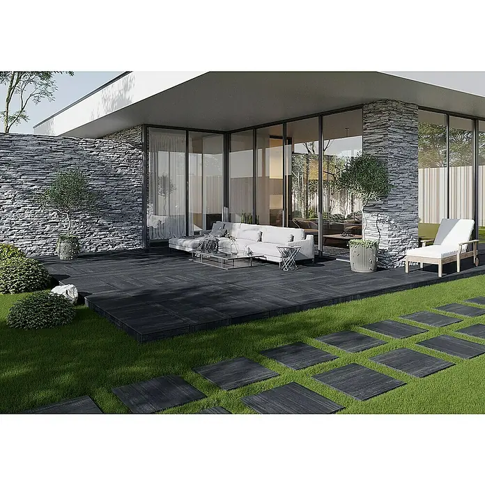 Terrassenfliese Garden Black Struktur - 59,7 x 59,7 x 2 cm, Schwarz, Matt - Eine moderne Terrasse mit dunklem Holzdeck, stilvollen Gartenmöbeln und einem gepflegten Rasenbereich mit Steinplattenweg.