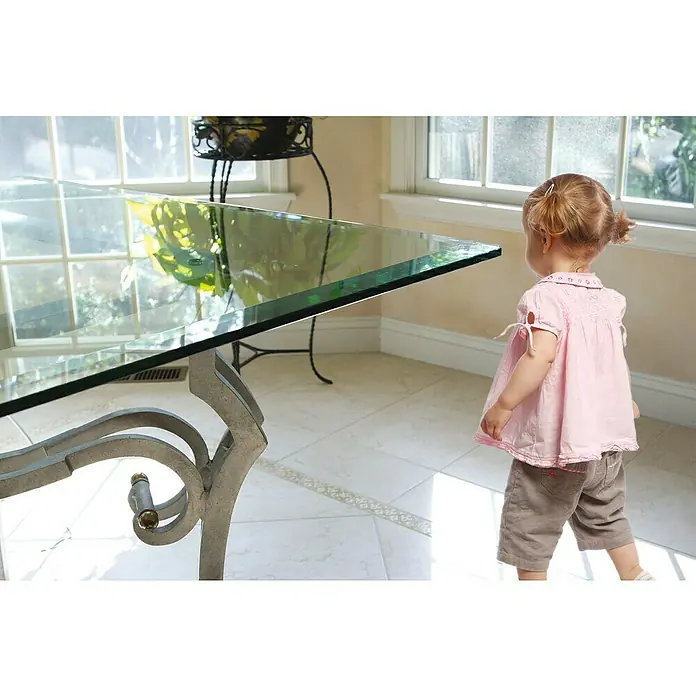 Dreambaby Glas-Eckenschutz - 4 Stk., Kleben - Nahaufnahme eines gläsernen Couchtisches mit einem verschnörkelten Metallgestell, der durch seinen modernen Stil besticht.