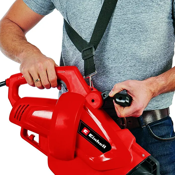 Einhell Aspirador de hojas eléctrico GC-EL 3024 E - 3.000 W, Velocidad de soplado: 240 km/h - Una persona operando el soplador de hojas rojo Einhell, que tiene una correa para el hombro.\n