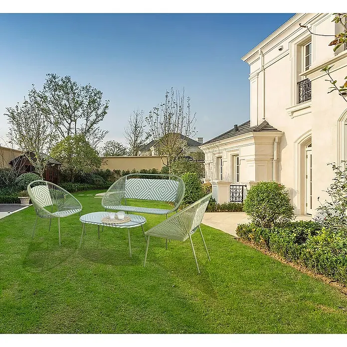 Conjunto de muebles Mariana - 4 pzs., Ratán sintético/Acero, Verde/Blanco - Juego de muebles de jardín con mesa y sillas sobre un césped verde frente a una casa elegante. Ideal para relajarse al aire libre.