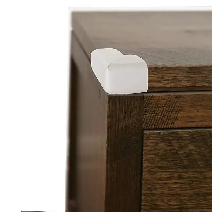 Dreambaby Eckenschutz - Grau, L x B x H: 40 x 35 x 15 mm, 4 Stk. - Weißer Eckenschutz auf einer dunklen Holzmöbelecke.
