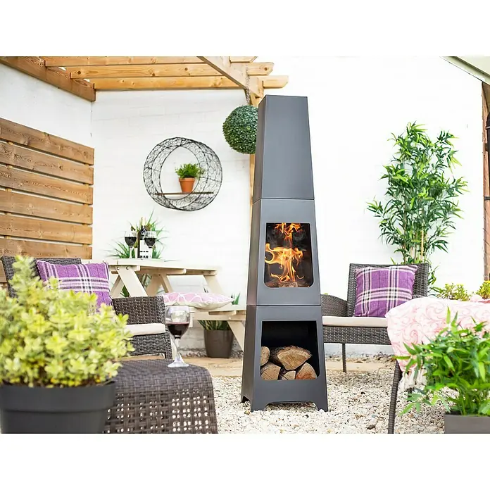 Buschbeck Chimenea para jardín Malmö - 36 x 36 x 150 cm, Acero, Recubrimiento en polvo - Acogedora escena al aire libre con una chimenea negra moderna, que aporta calidez y ambiente al patio.