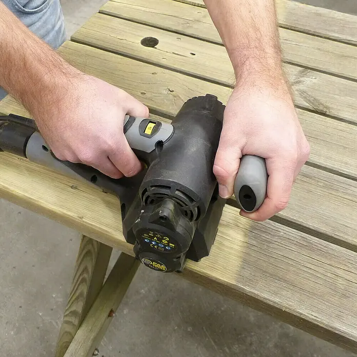 Fartools Renovierungsschleifer REX 80 Compact - 420 W - Nahaufnahme einer Person, die eine Farbspritzpistole auf einer Holzoberfläche verwendet.