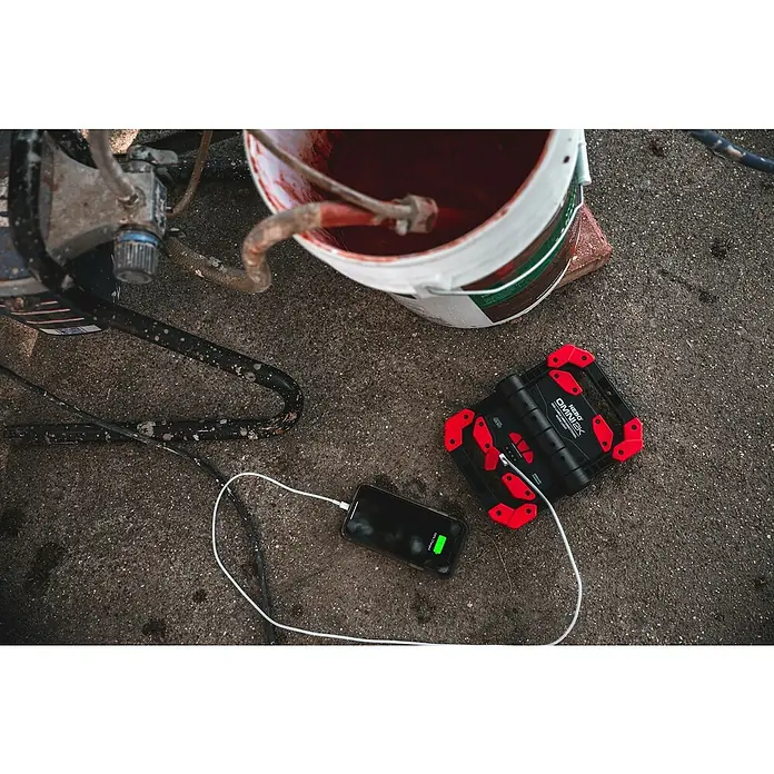 Nebo Tools Luz de trabajo LED Omini 2K - 2.000 lm - La luz de trabajo NEBO OMNI 2K está cargando un teléfono inteligente.