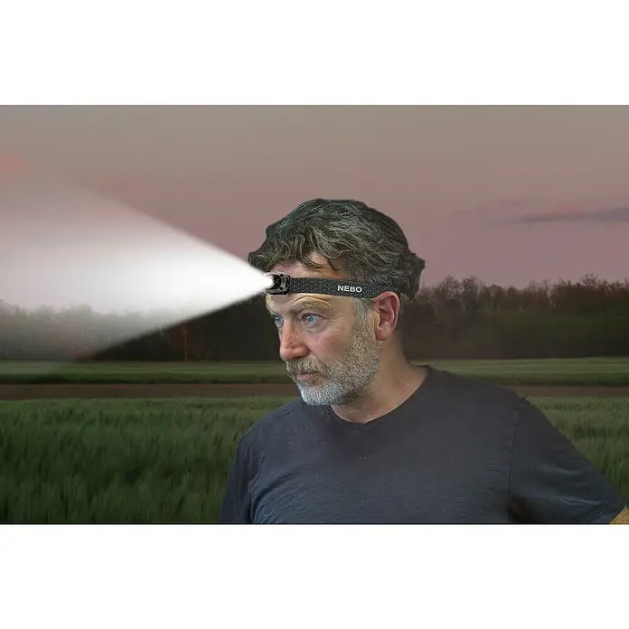 Nebo Tools Linterna frontal Mycro - 4,6 x 3,2 x 3,4 cm, 10 lm - 400 lm, IP67 - Primer plano de un hombre con una linterna frontal NEBO que brilla intensamente, ideal para actividades al aire libre en la oscuridad.