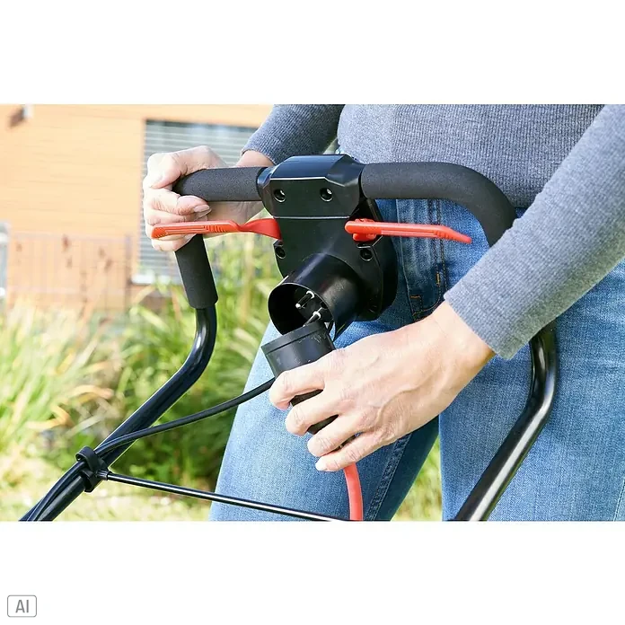 AL-KO Comfort Elektro-Rasenmäher - 1.200 W, Schnittbreite: 32 cm - Nahaufnahme einer Person, die ein Elektrokabel an einen Rasenmäher anschließt, wobei der Fokus auf dem schwarzen Griff und dem roten Kabel liegt.