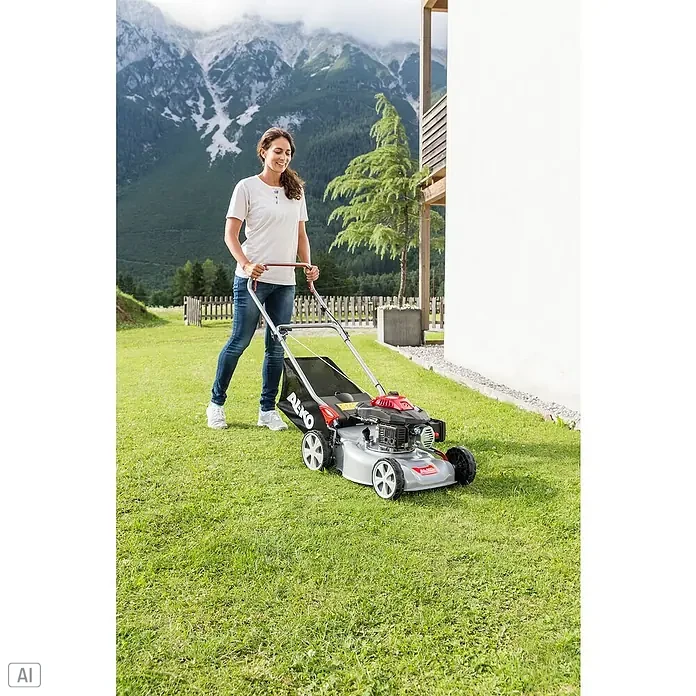 AL-KO Easy Benzin-Rasenmäher 4.20 P-S - 2 kW, 140 cm³, Schnittbreite: 42 cm - Eine Frau mäht den Rasen mit einem AL-KO Rasenmäher vor einer Bergkulisse. Der Rasenmäher ist silberfarben mit roten Akzenten.
