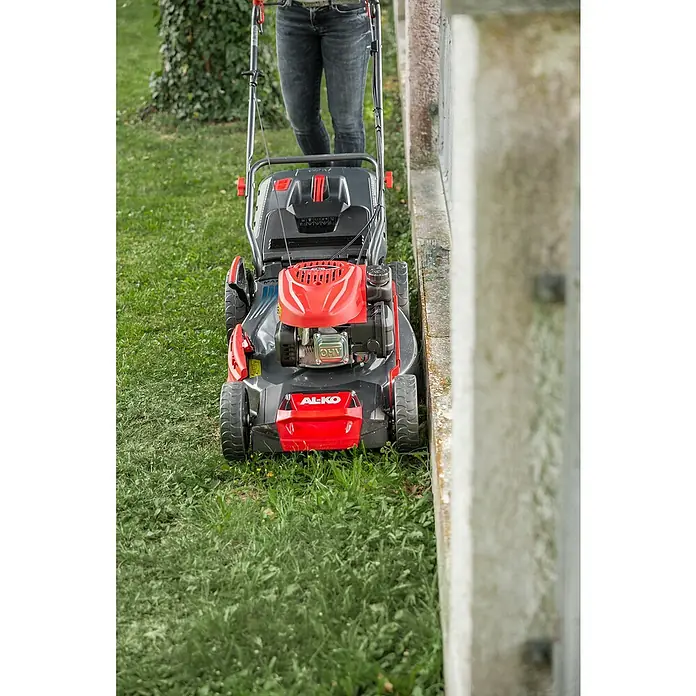 AL-KO Comfort Benzin-Rasenmäher 51.0 SP-A - 2,1 kW, 139 cm³, Schnittbreite: 51 cm - Ein AL-KO Rasenmäher in Aktion. Er ist rot und grau und wird von einer Person bedient, die auf einer grünen Rasenfläche steht.