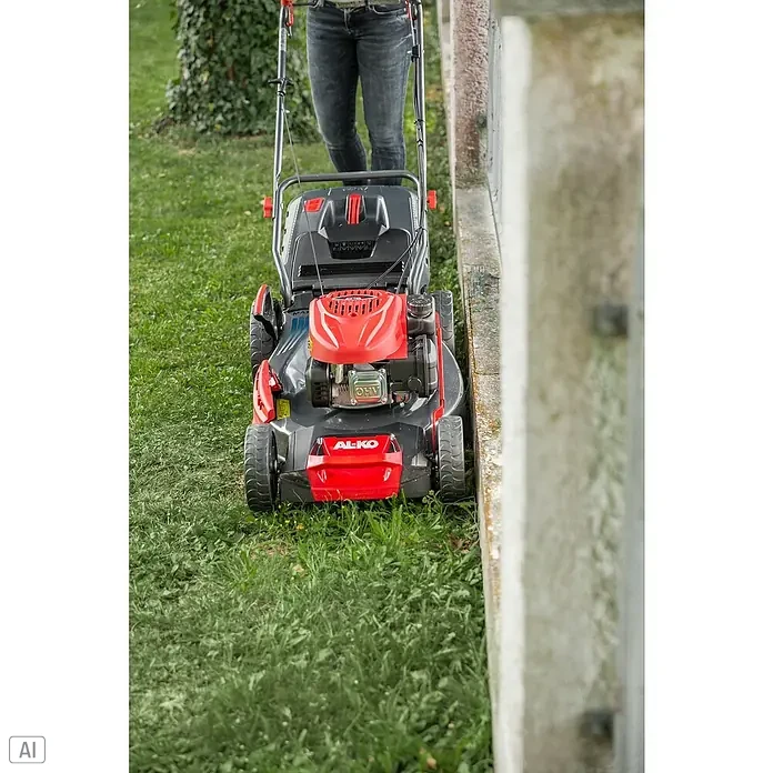 AL-KO Comfort Benzin-Rasenmäher 51.0 SP-A - 2,1 kW, 139 cm³, Schnittbreite: 51 cm - Ein AL-KO Rasenmäher in Aktion. Er ist rot und grau und wird von einer Person bedient, die auf einer grünen Rasenfläche steht.