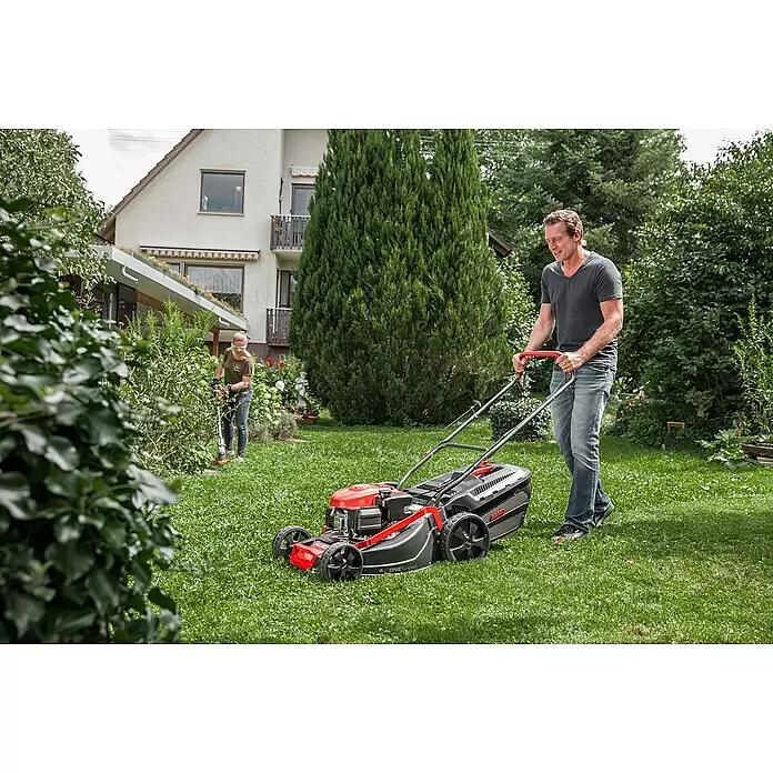 AL-KO Comfort Benzin-Rasenmäher 42.1 SP-A - 1,9 kW, 123 cm³, Schnittbreite: 42 cm - Ein Mann mäht mit einem rot-schwarzen Rasenmäher grünes Gras im Garten.