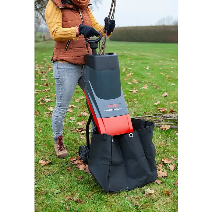 AL-KO Easy Elektro-Häcksler MH2500 Slice - Max. Aststärke: 4 cm, 2.500 W - Eine Person bedient einen AL-KO MH 2800 Slice Häcksler im Garten. Der Häcksler zerkleinert Äste und sammelt das Häckselgut in einem Sack.