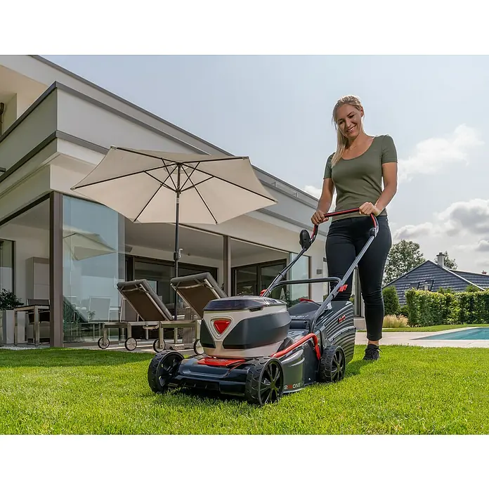 AL-KO 36V Akku-Rasenmäher 42.2 Li - 36 V, 1 Akku, 4 Ah, Schnittbreite: 42 cm - Frau bedient einen AL-KO Akku-Rasenmäher auf einem Rasen vor einem modernen Haus. Das Gerät ist kompakt und leicht zu bedienen.