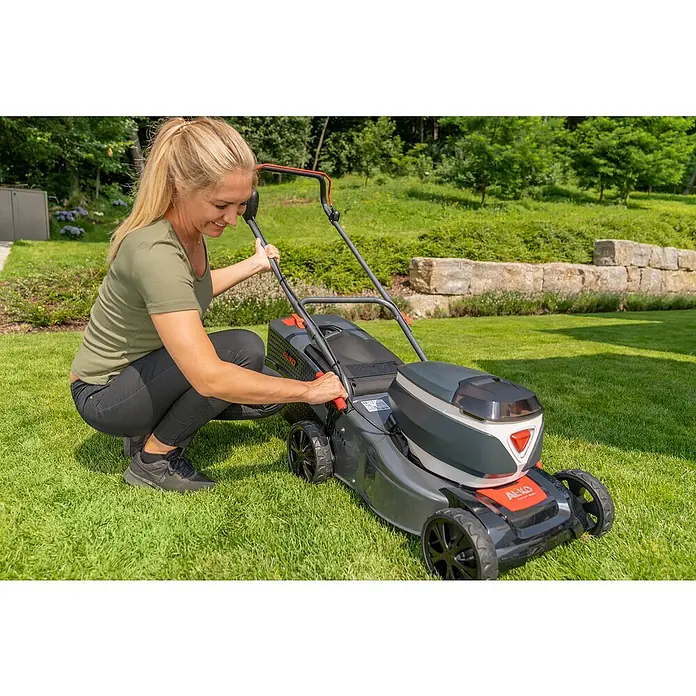 AL-KO 36V Akku-Rasenmäher 42.2 Li - 36 V, 1 Akku, 4 Ah, Schnittbreite: 42 cm - Eine blonde Frau bedient einen AL-KO Rasenmäher im Garten. Der Rasenmäher ist grau und schwarz, ideal für die Rasenpflege.