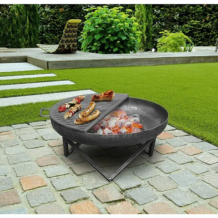 Buschbeck Grillrost Feuerschale - L x B: 29 x 57 cm - Ein Holzkohlegrill steht im Garten bereit, mit Würstchen und Spießen auf dem Rost. Gemütliche Atmosphäre für Grillabende im Freien.