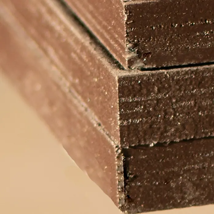 Tablero contrachapado fenólico - Abedul, 2.500 x 1.250 x 15 mm - Primer plano de múltiples capas de paneles de madera oscura apiladas, mostrando una textura interesante.