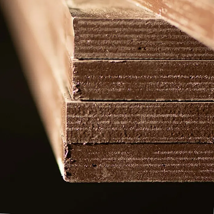 Tablero contrachapado fenólico - Abedul, 2.500 x 1.250 x 15 mm - Primer plano de una pila de cartón marrón, que muestra una textura y capas interesantes. Ideal para manualidades o embalaje.