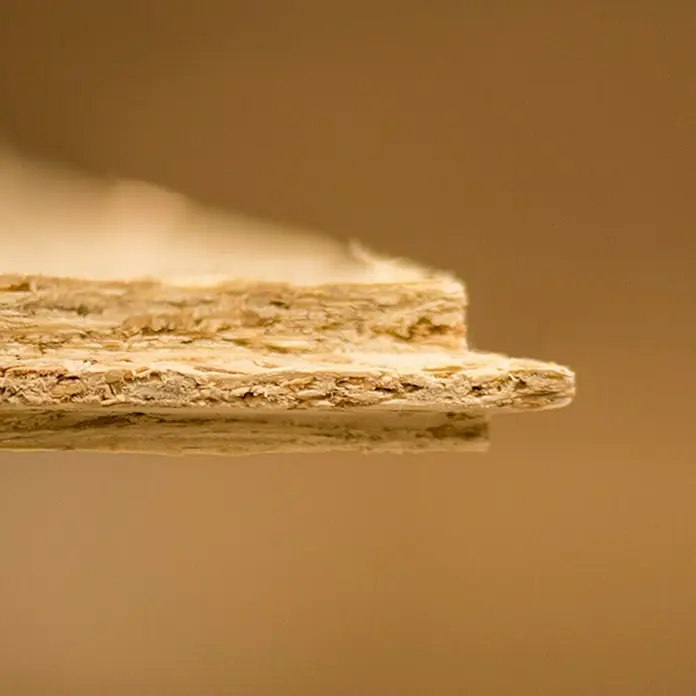 Tablero de OSB machihembrado - 250 cm x 67,5 cm x 16 mm - Primer plano de un tablero de fibra de madera, destacando su textura y capas. Ideal para la construcción y proyectos de bricolaje.